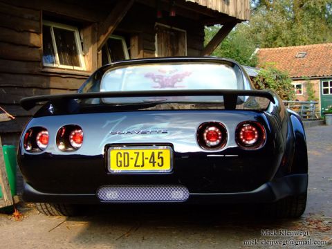 1976 Chevrolet Corvette - The rear of a black Chevrolet Corvette is visible, quad taillights and a spoiler.