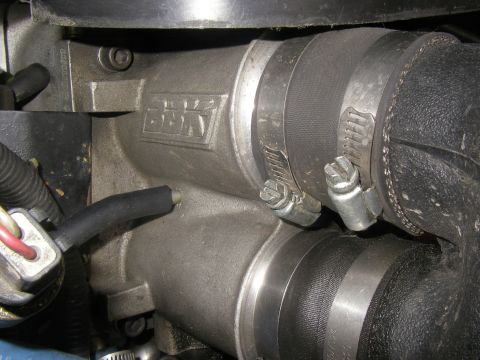 1990 Ford Bronco - Close-up of a BBK cast aluminum intake casting joined to rubber coupler hoses with worm-gear clamps in an engine bay.