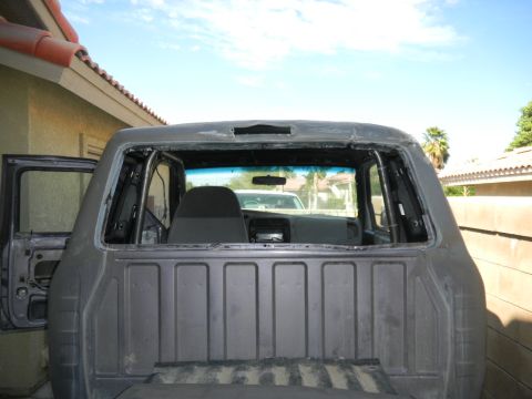 1997 Ford Ranger - Rear view of a gray Ford Ranger with a roll cage and removed doors, showing the interior and windshield.