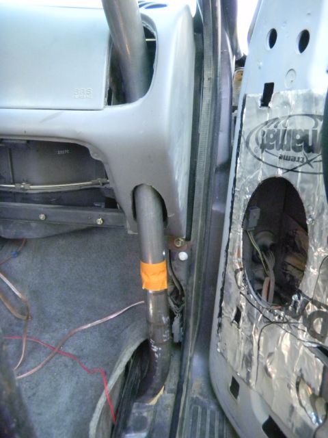 1997 Ford Ranger - The interior of a vehicle shows a roll cage tube running down the dashboard and door panel with sound deadening material.