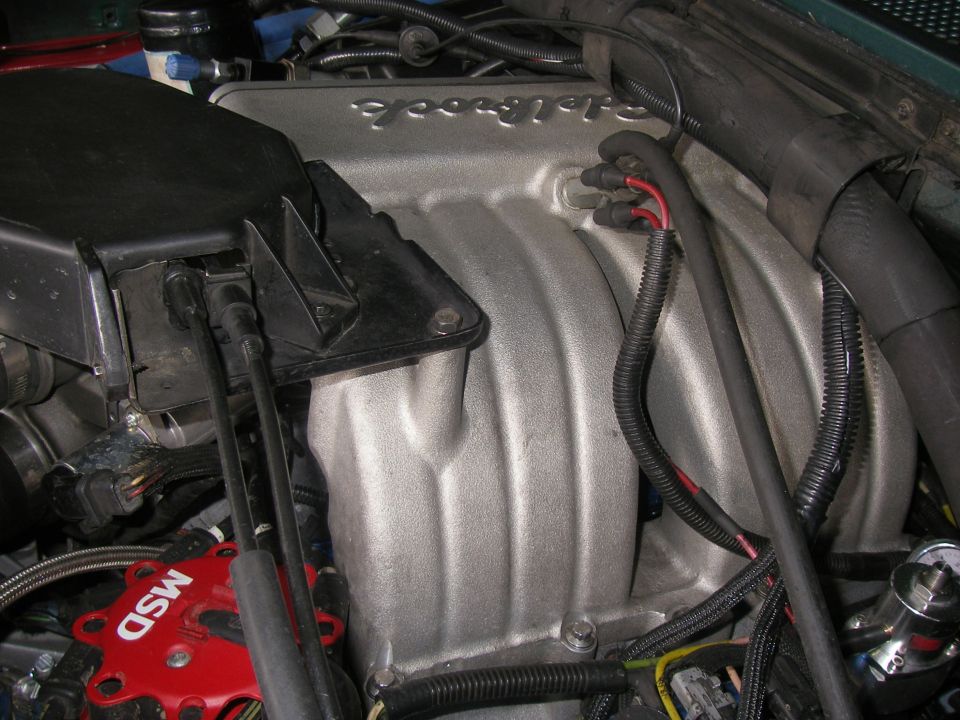 Cast aluminum Edelbrock EFI intake manifold installed with red MSD distributor cap nearby