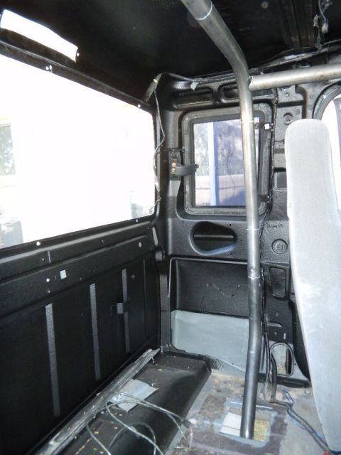 1997 Ford Ranger - The interior of a modified truck cab shows a roll cage and exposed wiring, with a grey seat visible.