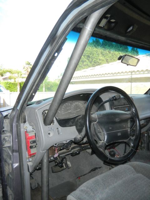 1997 Ford Ranger - Interior view of a 1997 Ford Ranger, showing the dashboard, steering wheel, and a prominent roll cage.