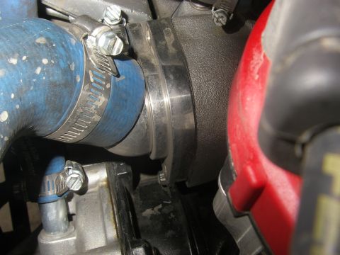 1990 Ford Bronco - Tight engine-bay close-up of a stainless thermostat housing joined to a blue silicone upper radiator hose with stainless worm-gear clamps.…