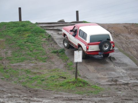 1991 Ford Bronco - This two-tone Ford Bronco navigates a challenging off-road course with a muddy incline.