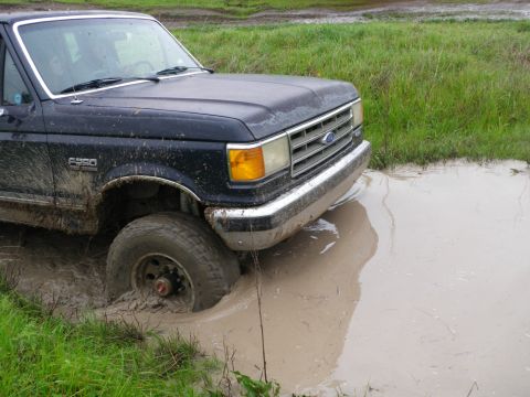 1991 Ford Bronco - Muddy 1991 Ford F-350 stuck in a water-filled ditch off-road.