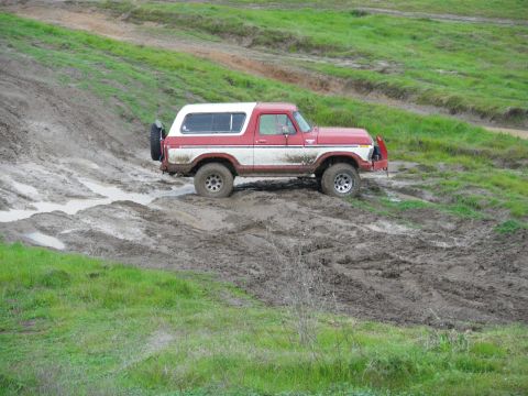 1991 Ford Bronco - This red and white Ford Bronco is navigating a muddy off-road course.