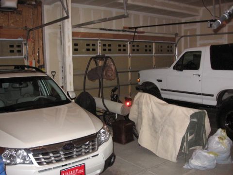 1995 Ford Bronco - Two vehicles are parked inside a garage, with one partially covered by a cloth.