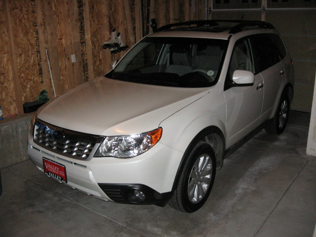 Pearl white compact crossover SUV parked in an unfinished garage, dealer plate on front