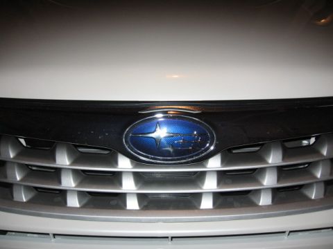 1995 Ford Bronco - Close-up of a white Subaru's front grille and emblem.