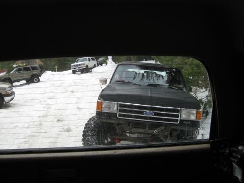 1986 Ford Bronco - Several off-road vehicles are parked in a snowy area, with a black pickup truck prominently in the foreground.