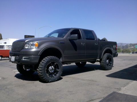 2005 Ford F-150 - Lifted 2005 Ford F-150 pickup truck with custom wheels and tires parked on pavement.