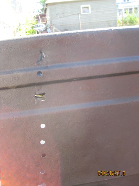 1983 Ford Bronco - Close-up of a brown tailgate support showing several holes and a metal clip. The date 04/24/2010 is visible in the corner.