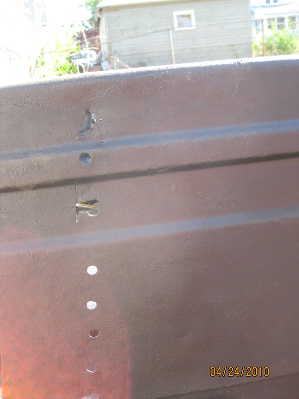 Brown tailgate support with holes and a visible clip