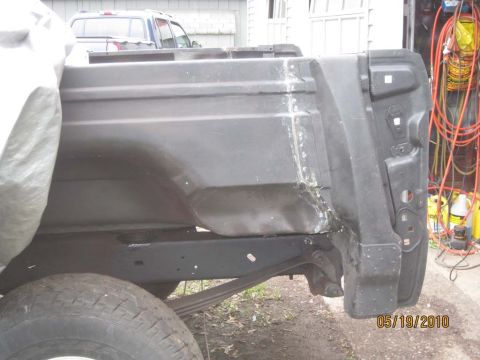 1983 Ford Bronco - The rear section of a truck bed shows damage and repair work, with another vehicle visible in the background.
