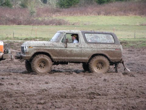 1978 Ford Bronco - A heavily mud-splattered 1978 Ford Bronco navigates a challenging muddy terrain.