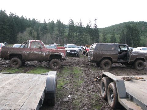1978 Ford Bronco - Several off-road vehicles are stuck in the mud after an event, with trailers in the foreground.