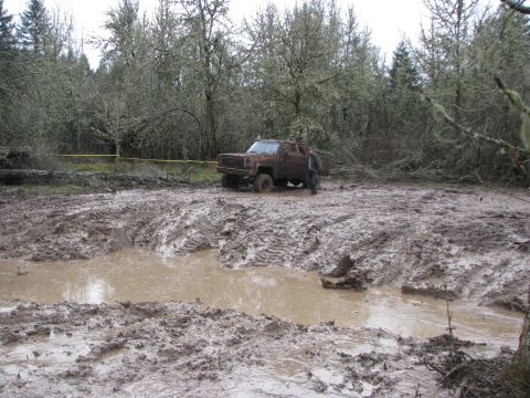1978 Ford Bronco - Off-road vehicle stuck in deep mud with trees in background.