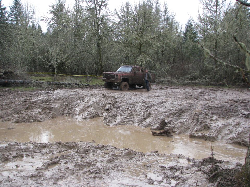 Off-road vehicle stuck in deep mud with trees in background