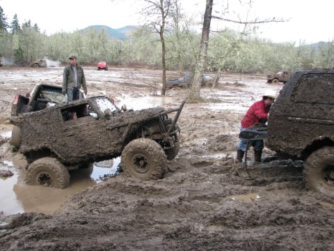 1978 Ford Bronco - Multiple off-road vehicles are stuck in thick mud during an event.