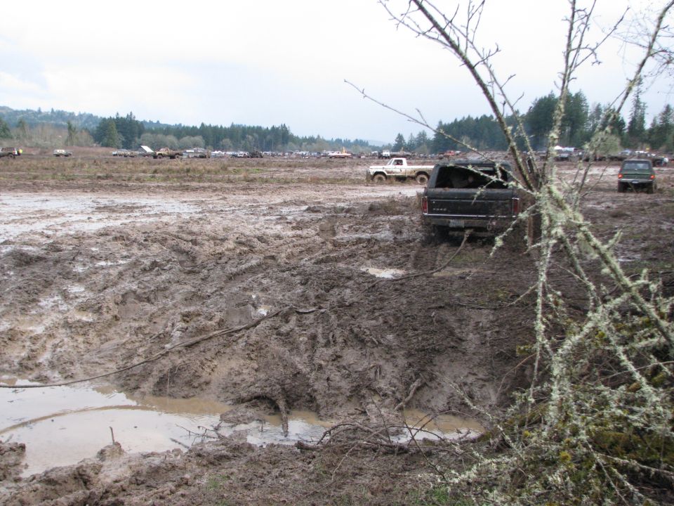 truck stuck in mud pit, other trucks in background