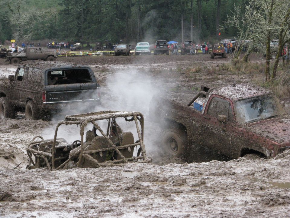 Mud-covered 1978 Ford Bronco driving through mud, emitting steam