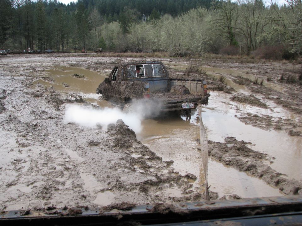 Pickup truck stuck in mud, kicking up white smoke