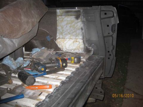 1983 Ford Bronco - Interior view of a stripped body tub with a freshly welded bare-metal replacement panel in the rear corner, still showing grinding marks an…