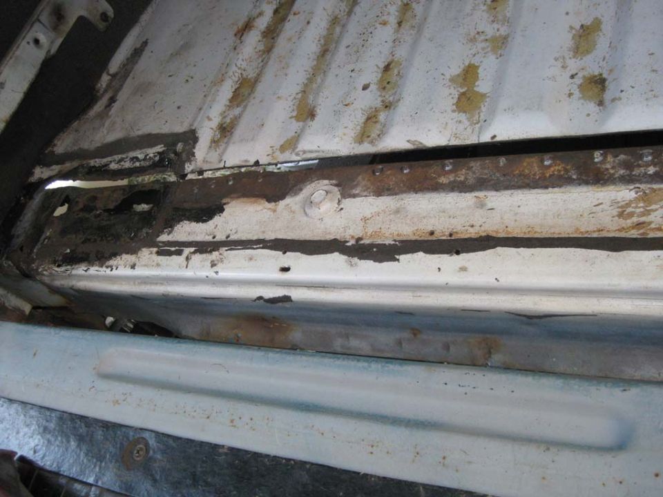 Rusty tub support rail with body-mount bolt beside a white Bronco floor pan