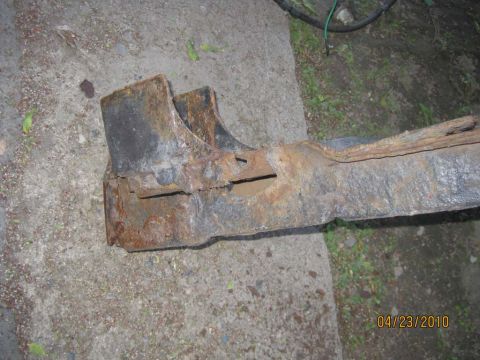 1983 Ford Bronco - A heavily rusted metal component, possibly from a vehicle's frame, lies on a concrete surface.