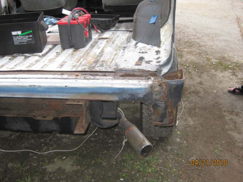 Stripped white body tub with quarter panel cut away exposing rusted rear corner structure