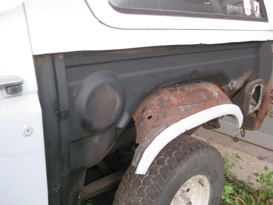 Bronco with quarter panel removed showing rusty inner wheelhouse and white patch panel