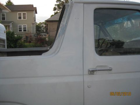 1983 Ford Bronco - Side view of the driver's door and new quarter panel on a topless white Bronco, focused on the door-to-quarter gap and the primered, filled…