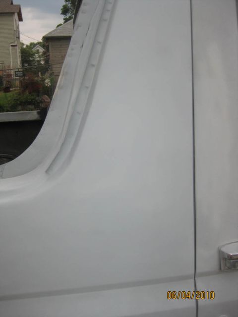 1983 Ford Bronco - Close-up of the blocked-and-primered joint where a Bronco's rear quarter meets the door and cab, the filler sanded smooth and uniform light…