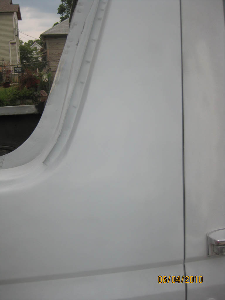 Sanded gray primer on a Bronco quarter-to-door panel seam, chrome handle at right
