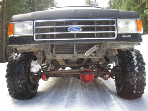 1989 Ford Bronco - This lifted Ford truck is equipped with large off-road tires and appears ready for snowy conditions.