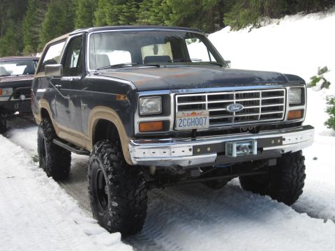 1989 Ford Bronco - Ford Bronco parked on a snow-covered road with trees in the background.