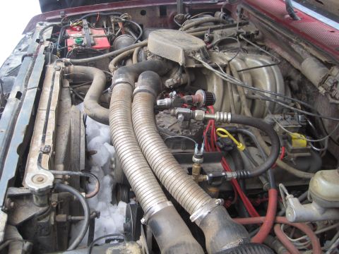 1989 Ford Bronco - The engine bay of a maroon Ford Bronco shows snow accumulation around the radiator and hoses, suggesting a cold climate.