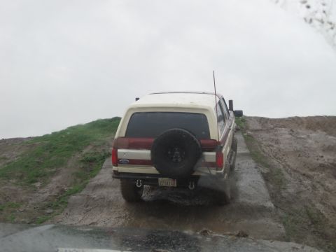 1989 Ford Bronco - Rear view of a 1989 Ford Bronco navigating a wet, muddy trail.