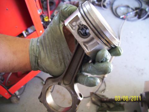 1995 Ford Probe - A gloved hand holds an engine piston and connecting rod, with a date stamp and website visible in the background.