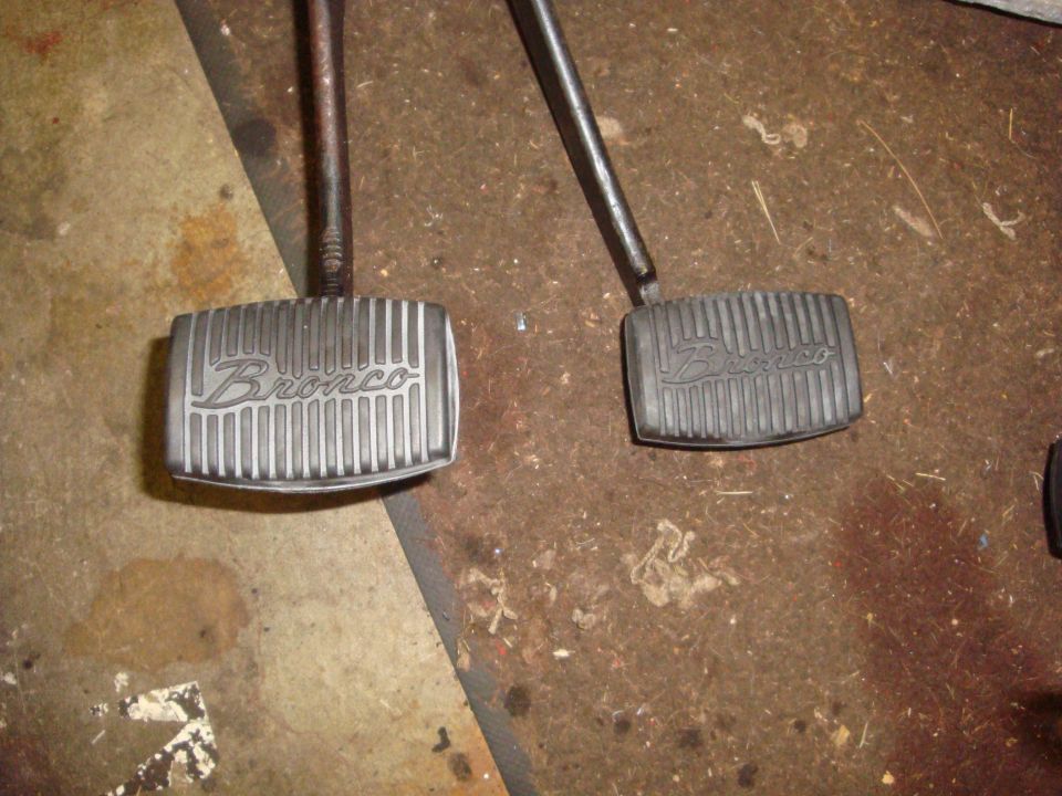 Two metal pedals with "Bronco" embossed on them, one silver and one black