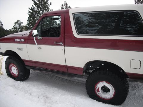 1991 Ford Bronco - Side view of a two-tone red and white 1991 Ford Bronco in a snowy environment.