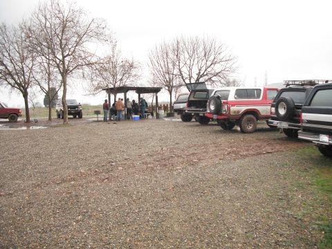 1991 Ford Bronco - Several SUVs are parked at a picnic area with people gathered under a shelter.