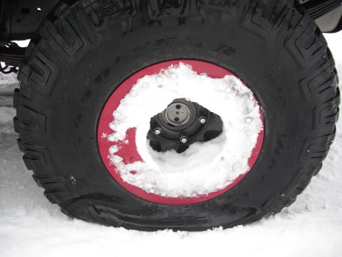 1991 Ford Bronco - Close-up of a tire with a red rim, partially covered in snow.