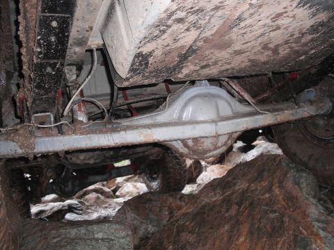 1991 Ford Bronco - Vehicle's undercarriage and rear axle are visible while navigating rocky terrain.