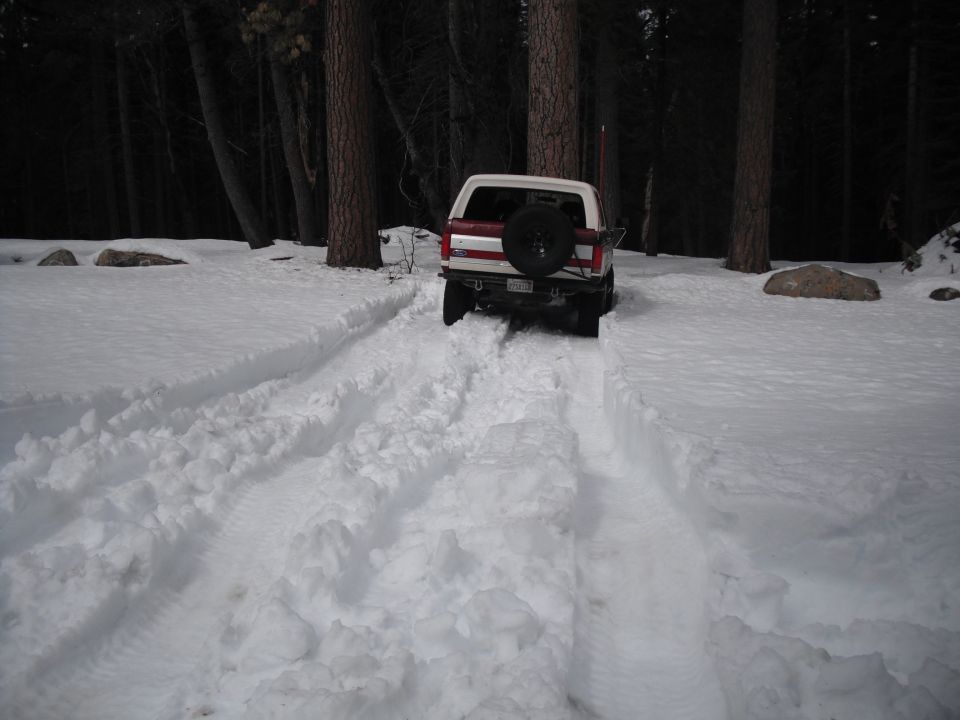 1991 Ford Bronco driving on a snow-covered road, rear view