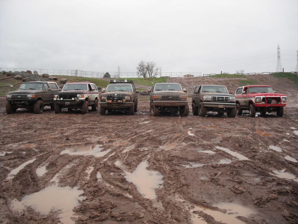 Six SUVs parked in a muddy field under an overcast sky