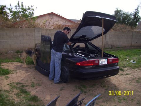1995 Ford Probe - Man works on a 1995 Ford Probe with its trunk and doors open in a yard.