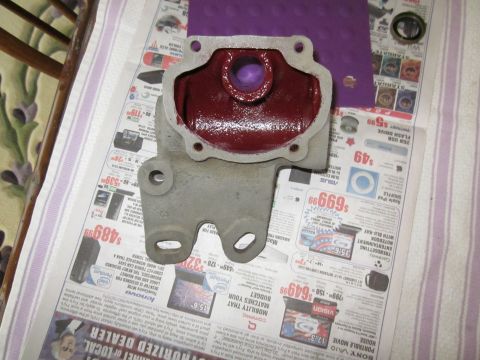1979 Ford Bronco - A metal automotive part, likely a housing, is covered in red grease and placed on a surface covered with old newspapers.