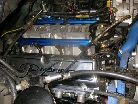 1990 Ford Bronco - Tight engine bay shot of a built Ford small-block V8 with a polished Ford Racing valve cover, bare aluminum upper intake and blue anodized…